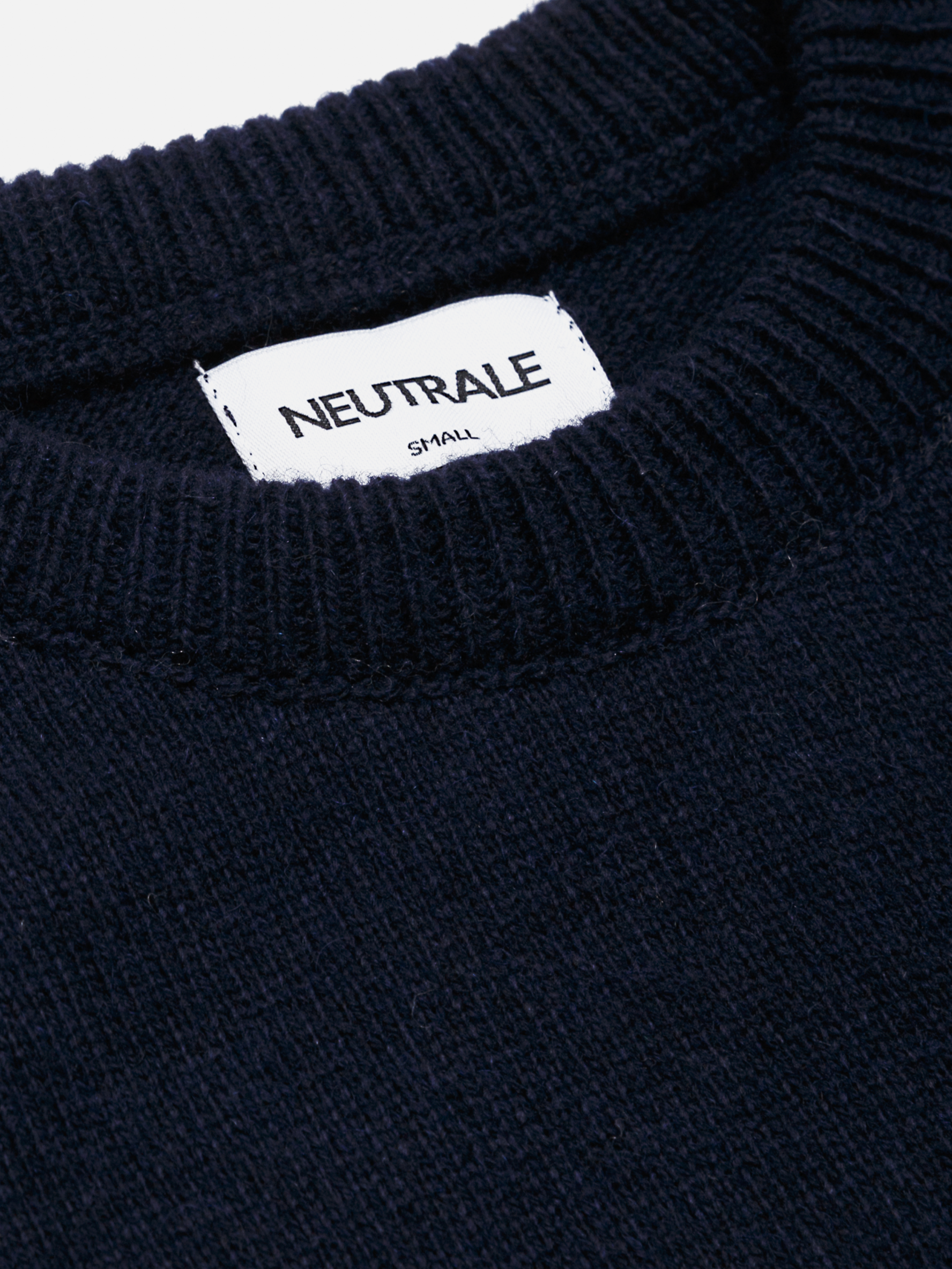 Neutrale dark navy knit sweater with a relaxed fit, featuring ribbed cuffs, hem, and collar. Crafted from a blend of wool and organic cotton.